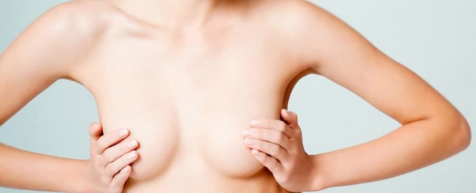 figura feminina com a mão nos seios para ilustrar a plástica de mamas